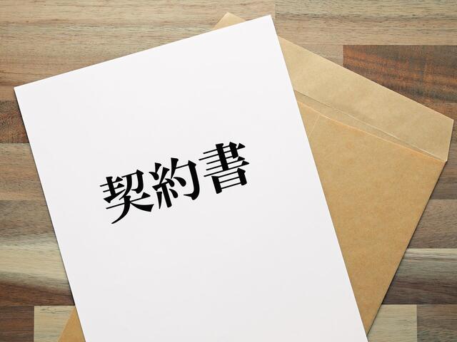 契約書と茶色の封筒が机に置かれる